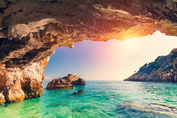 Sun setting through a sea cave arch in Zakynthos